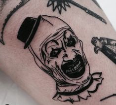 a close up of a person's arm with tattoos on it and an image of a clown