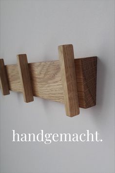 a wooden coat rack on the wall with words underneath it that read, handgemacch