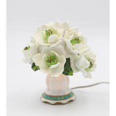 a white flower arrangement in a ceramic vase with a cord plugged into the charger