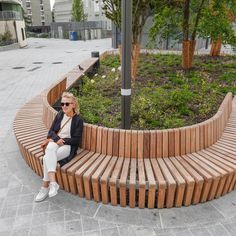 a woman sitting on top of a wooden bench