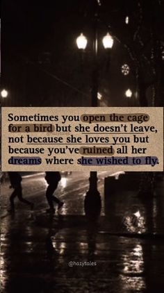 two people walking down the street in the rain at night and one has a quote on it