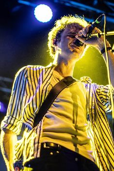 a man in striped shirt singing on stage