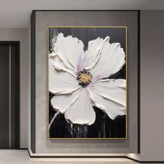 a large white flower on a black and gold background in a room with grey walls