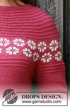 a woman wearing a pink sweater with white flowers on it