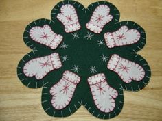 a green and white flower with red stitches on the petals is sitting on a wooden surface