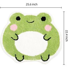 a green frog rug with pink cheeks and eyes on it's face is shown in front of a white background