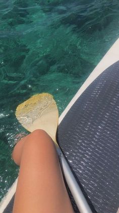 a person is sitting on a boat in the water with their feet propped up against the edge