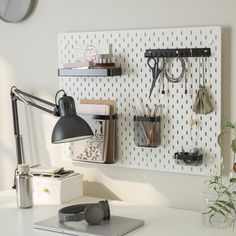 a desk with a laptop, headphones and various office supplies on the pegboard