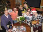 a group of people are posing for a photo in front of a christmas tree with gifts