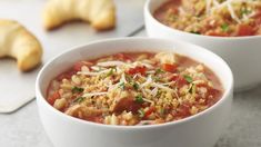 two white bowls filled with soup on top of a table