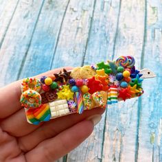 a hand holding a tiny toy house made out of candy and candies on it