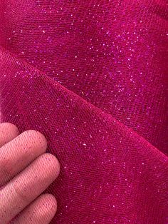 a hand is holding onto a pink fabric