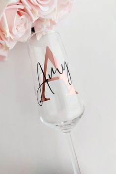 a wine glass with the word ava written on it next to pink roses and flowers