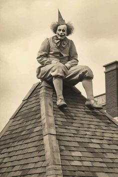 a creepy clown sitting on top of a roof