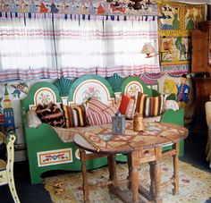 a living room filled with lots of furniture and colorful curtains on the window sill