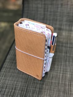 a wallet with several pens and pencils in it sitting on a table next to a couch