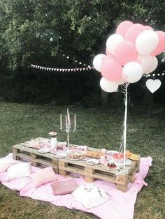 a picnic table with pink and white balloons