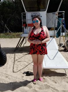 a woman in a red and black swimsuit standing on the beach