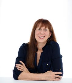 a woman sitting at a table with her arms crossed and looking up to the side