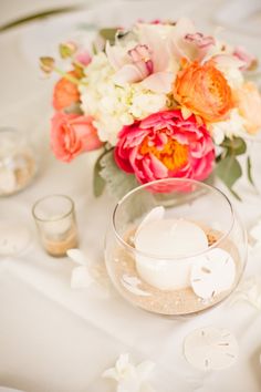 flowers and candles on a table with white linens for a centerpiece or decoration