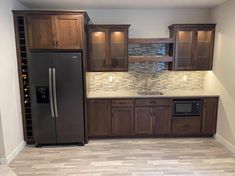 a kitchen with wooden cabinets and stainless steel refrigerator freezer combo in the center, along with tile flooring