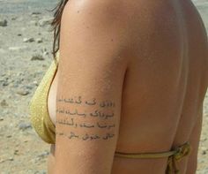 the back of a woman's body with arabic writing on her arm and chest