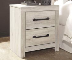 a white night stand with two drawers and a lamp on top of the nightstand next to it