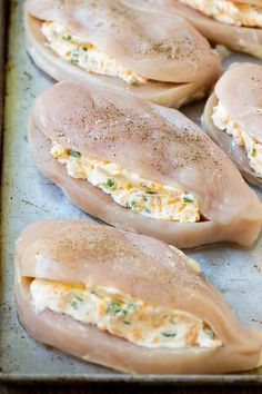 several pieces of chicken sitting on top of a baking pan covered in cheese and seasoning