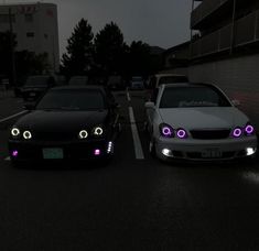 two cars parked next to each other in the street with purple lights on their headlights