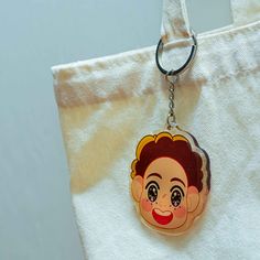 a keychain with a cartoon character hanging from it's front end on a white tote bag