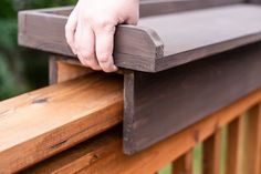 a person's hand on the top of a wooden rail