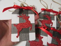 someone is holding three christmas gift tags with red glitter deer on them