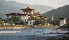 a bridge over a river in front of a large white building with gold trimmings