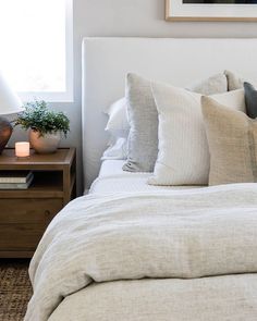 a bed with white linens and pillows on top of it next to a night stand