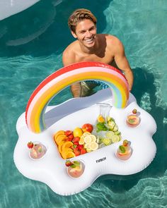 a man sitting in the water with a rainbow shaped pool float on it's side