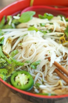 a red bowl filled with noodles and vegetables