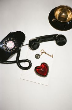 an old fashioned telephone with a red heart on it and a key to the phone