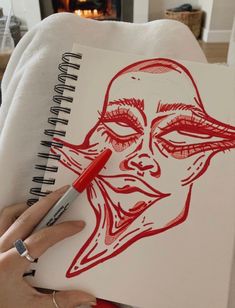 a drawing of a woman's face is being drawn in red on white paper