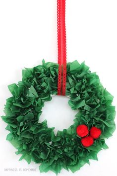 a green wreath with red balls hanging from it's side on a white background