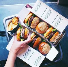 two boxes filled with hamburgers and fries sitting on top of a metal tray next to each other