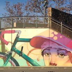 a mural on the side of a building with bicycles and a woman's face painted on it