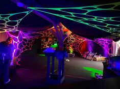 a man standing under a tent covered in neon lights