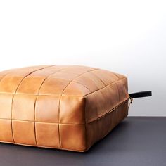 a brown leather ottoman sitting on top of a table