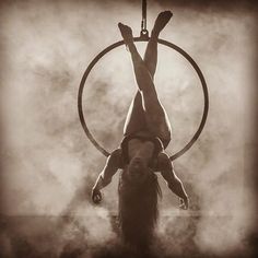 a man is doing tricks on a hoop with his hands and feet in the air