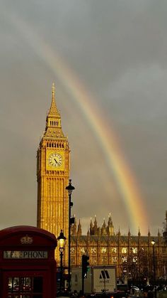 the big ben clock tower towering over the city of london with a rainbow in the sky