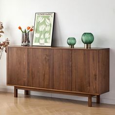 a wooden sideboard with vases on top of it next to a potted plant