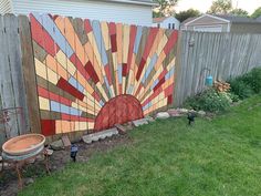 a fence with a painting on it next to a yard and some grass in front of the fence