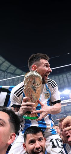 a soccer player is holding the trophy in front of his head while other players look on