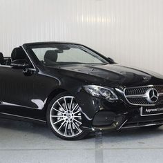 a black mercedes s - class cab is parked in front of a white garage wall