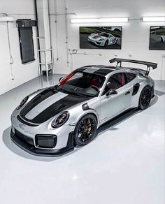 a silver and black sports car parked in a garage with two pictures on the wall